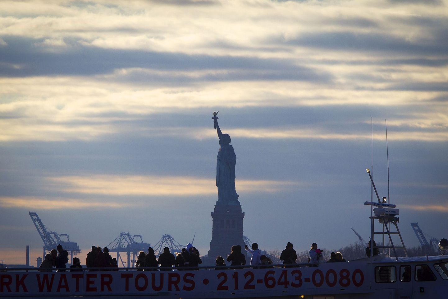 The Statue of Liberty is pictured behind a tourist boat in Battery Park in the Manhattan borough of New York, December 18, 2014. REUTERS/Carlo Allegri (UNITED STATES - Tags: SOCIETY TRAVEL CITYSCAPE)