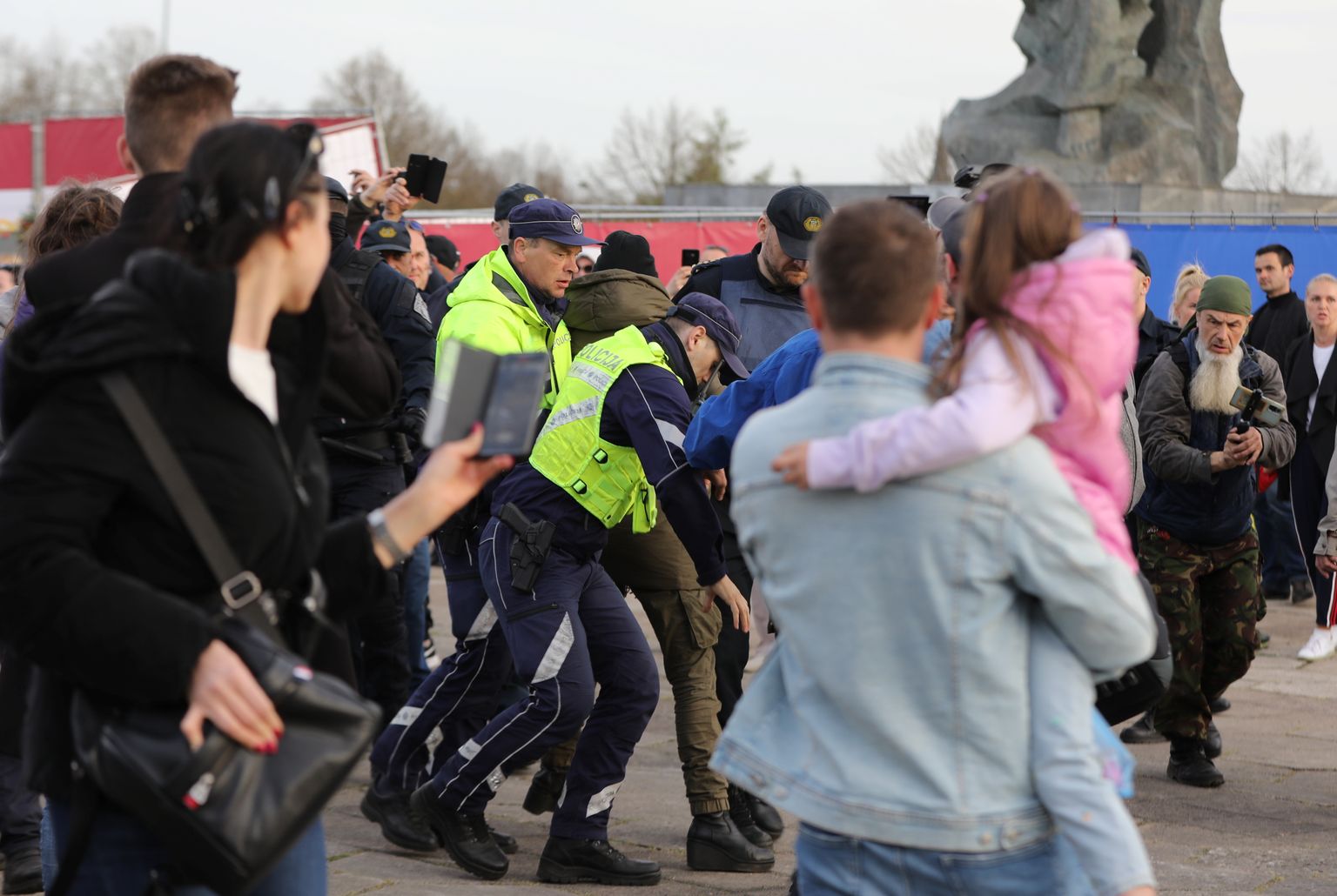 Valsts policijas darbinieki aiztur sievieti 10. maija vakarā pie pieminekļa Pārdaugavā, kur turpinās pulcēšanās un ziedu nolikšana.