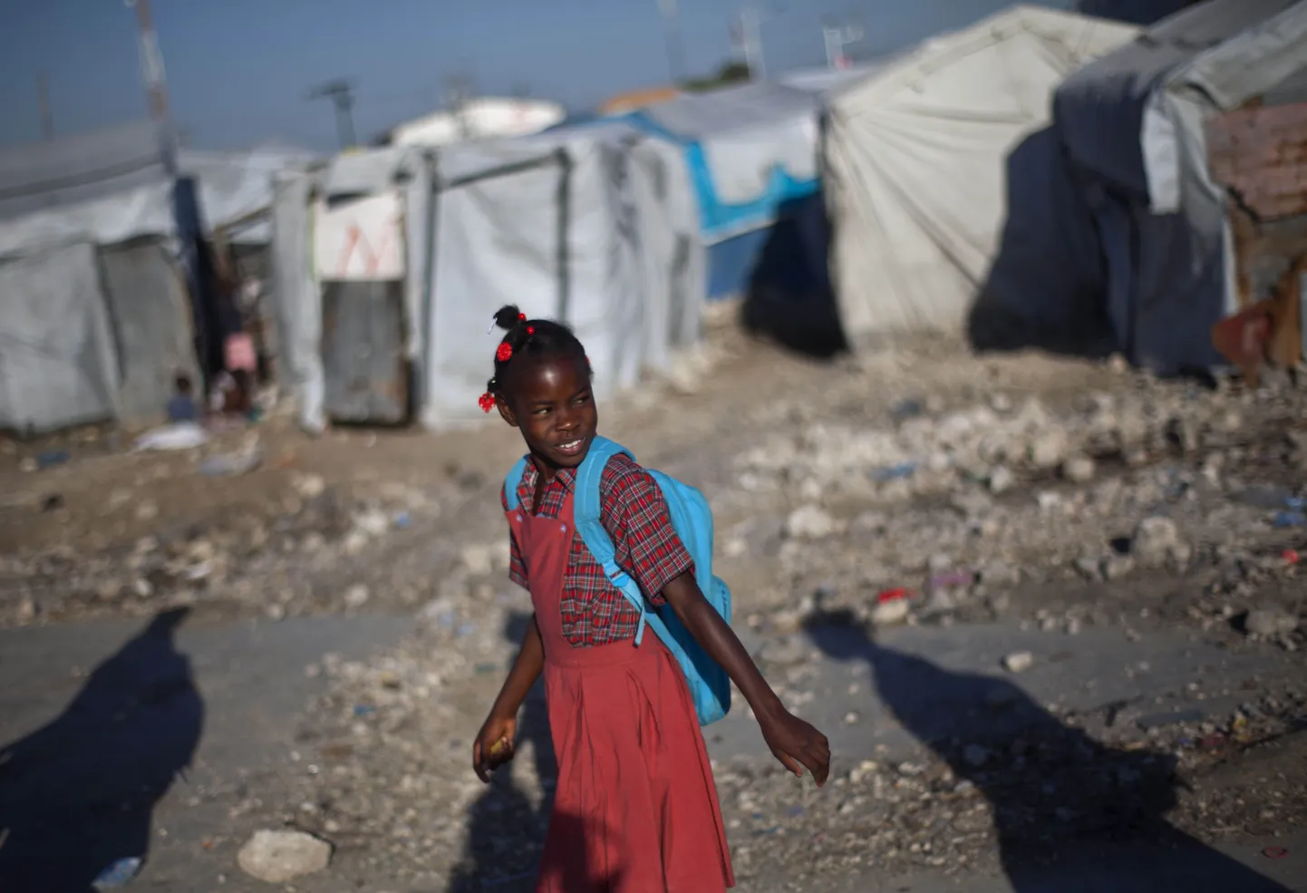 Haiti tüdruk läheb kooli. Taga paistab põgenikelaager, mis pandi püsti pärast  Port-au-Prince'i raputanud maavärinat 2010. aastal ehk kaks aastat tagasi.