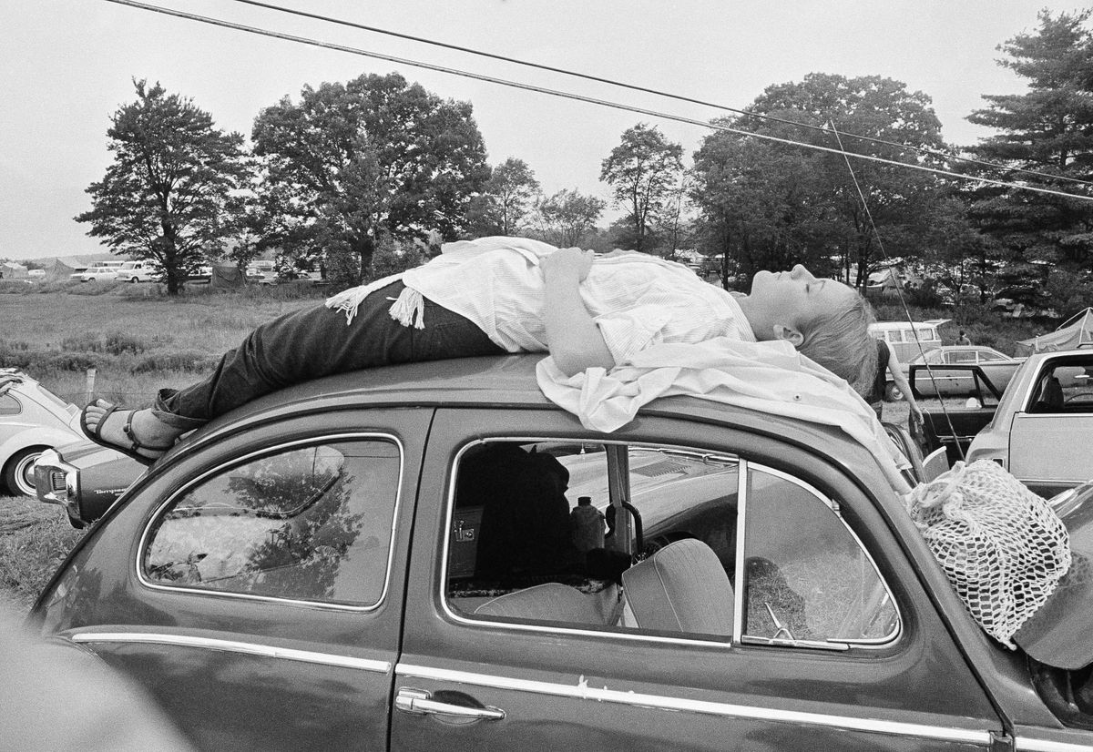 1969. gada 15. augusts. Uz festivālu ir pārdotas 186 tūkstoši biļešu, taču tajā ieradās krietni vairāk cilvēku - ap 400 tūkstošiem. Arī šī dāma redzama, guļot uz sava auto un mēģinot nokļūt Vudstokas festivāla teritorijā.
