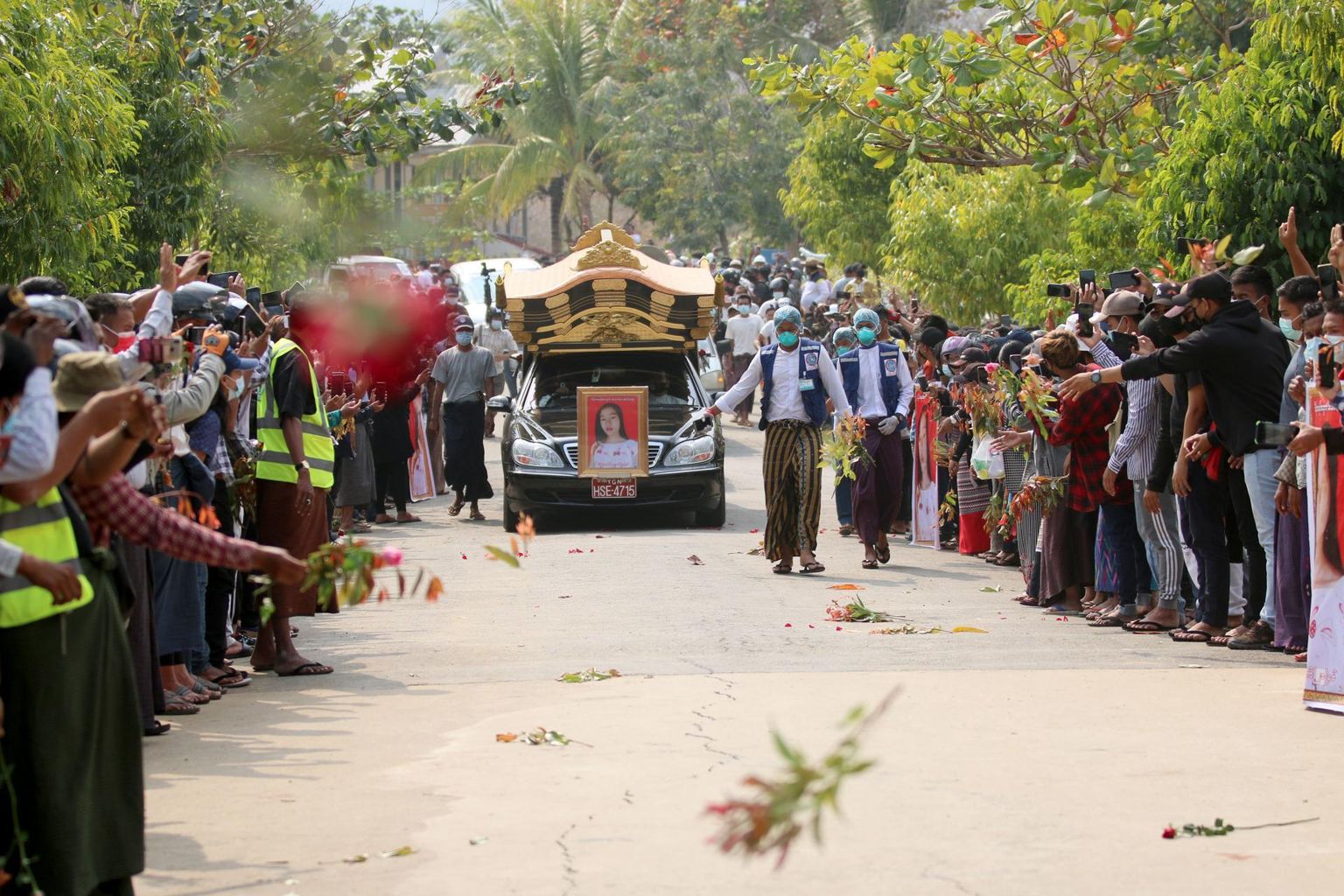 Myanmari elanikud viskamas lilli matuseauto ette.