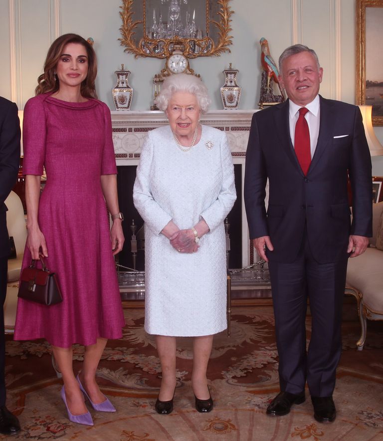 Briti kuninganna Elizabeth II poseerimas koos Jordaania kuninganna Rania ja kuningas Abdullah II. Elizabeth II vasakul käel on näha suurt lillakaspunast laiku
