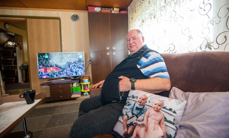 Alar Tupp at home in Mustvee at one of his favorite activities, watching sports. The sofa cushion has a picture of his two grandchildren. He has a total of six grandchildren.
