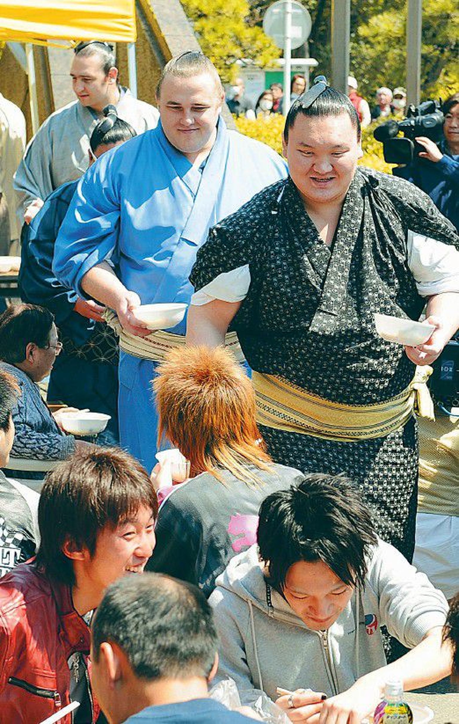 Hakuho (esiplaanil) ja Baruto jagavad inimestele spetsiaalset sumorooga.