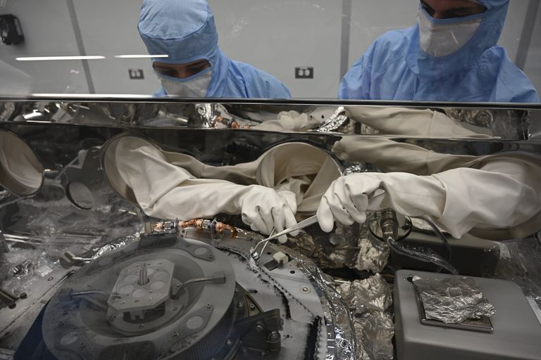 Fotol kasutavad Mari Montoya (vasakul) ja Curtis Calva (paremal) spetsiaalseid tööriistu, et koguda asteroidiosakesi kapsli põhjast.