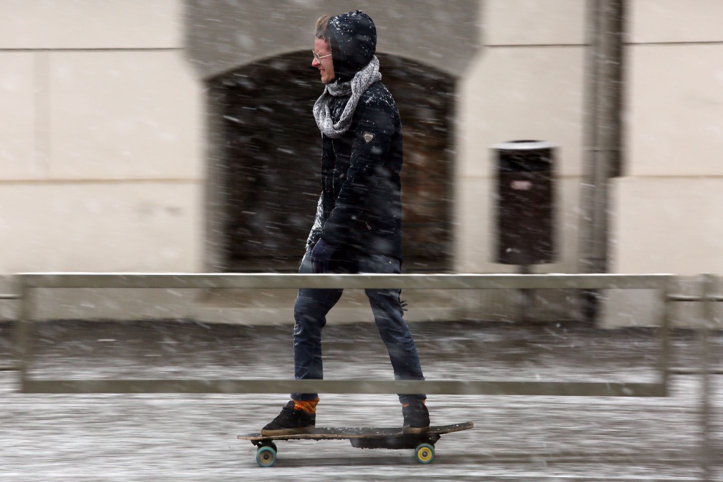 Парень на скейте во время снегопада в Риге