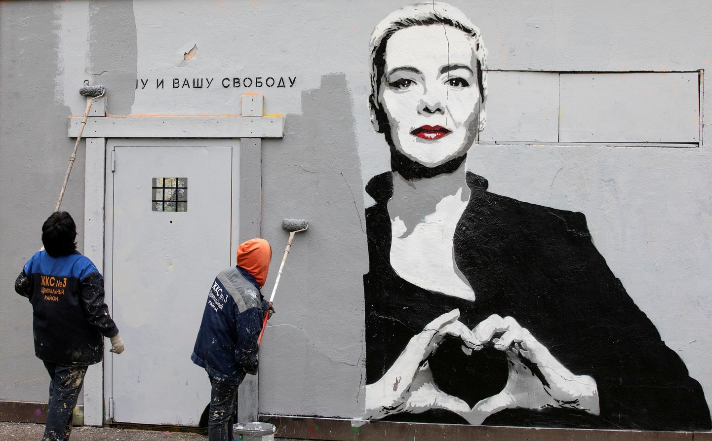 Strādnieki 2021. gada 8. septembrī Sanktpēterburgā aizkrāso grafiti, kurā attēlota ieslodzītā Baltkrievijas opozīcijas politiķe Marija Koļesņikova
