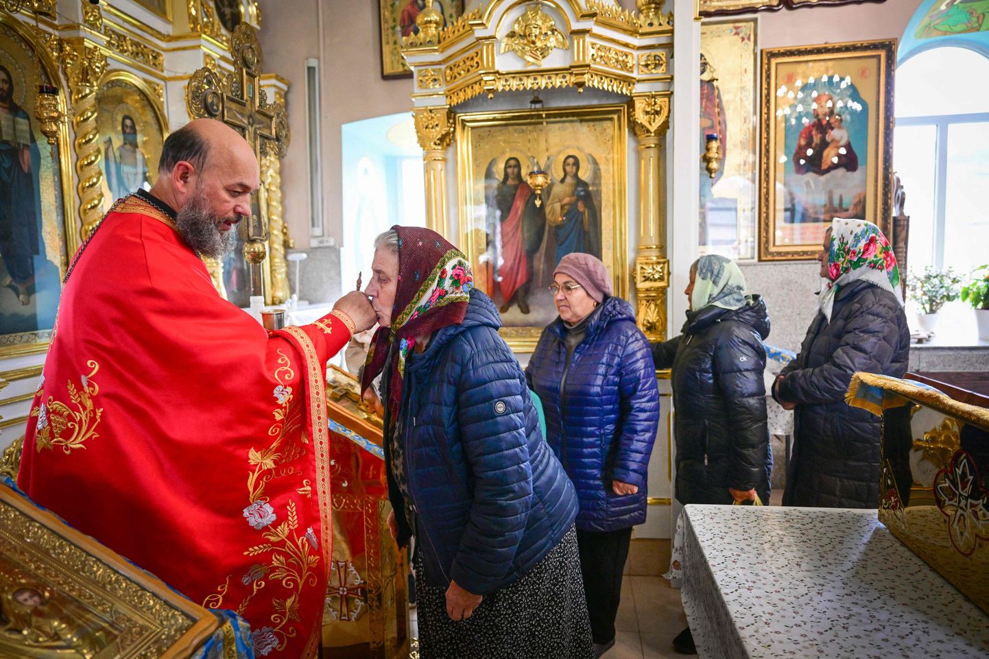 Молдавский православный священник Иоанн Солонару благословляет верующих в церкви в деревне Чимишены.