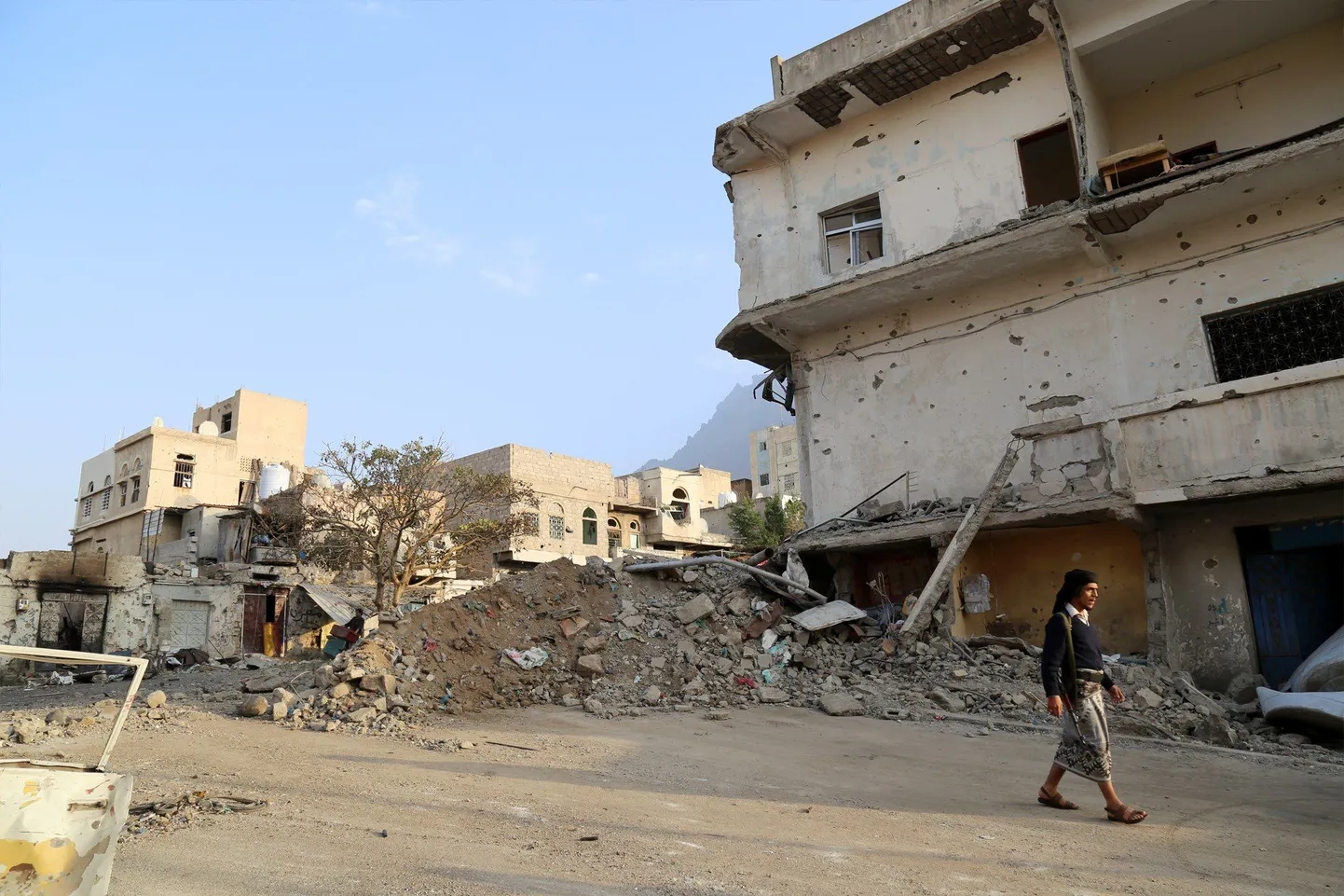 Relvastatud mees eile Jeemeni linnas Ta'izzis purustatud hoonete vahel.
