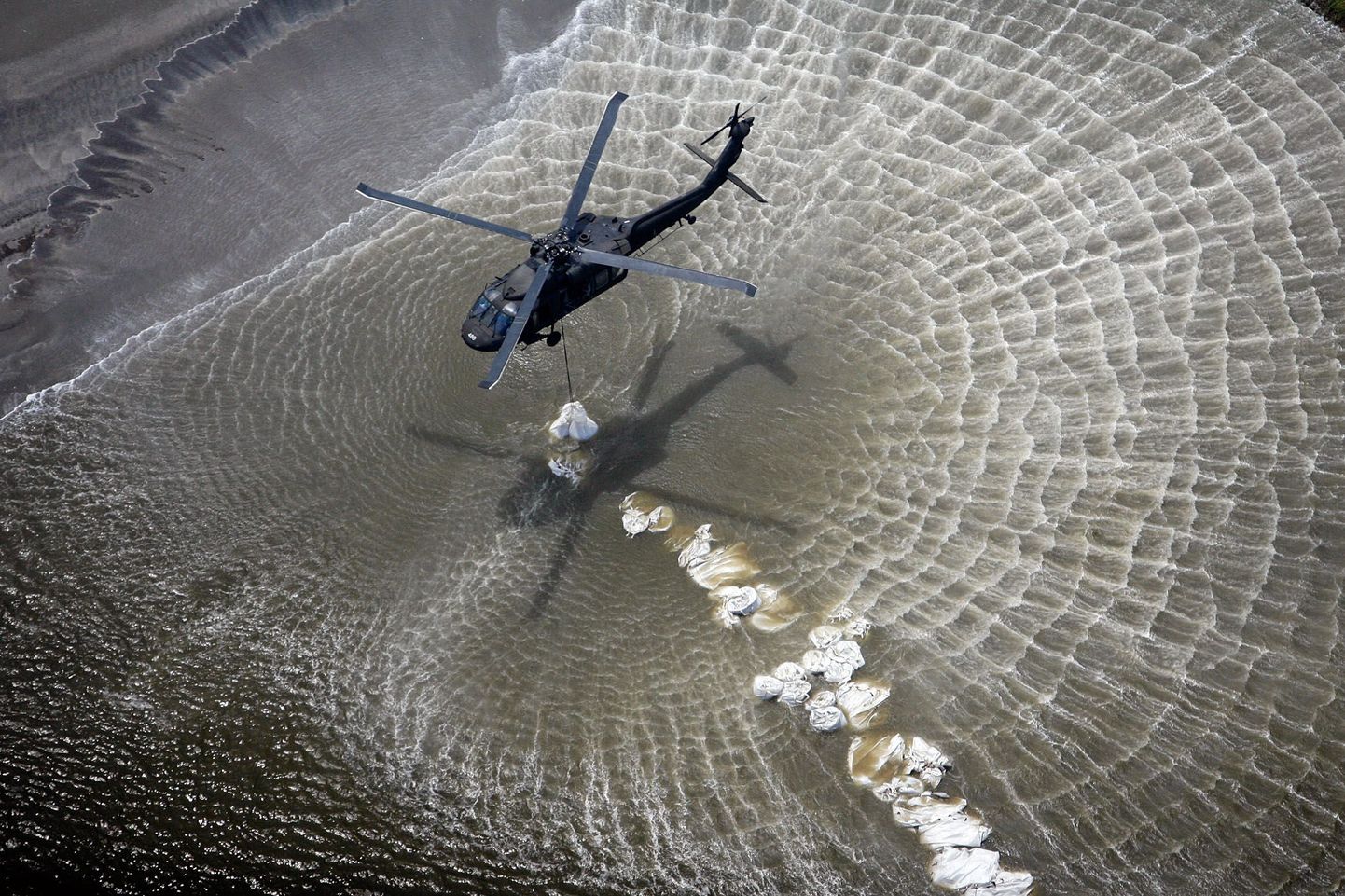 Вертолеты Национальной гвардии строят заграждение из мешков с песком у островов около побережья Луизианы.