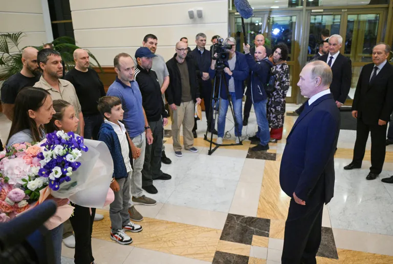Путин в московском аэропорту общается с освобожденными из иностранных тюрем россиянами. Брат священника Леонида Конощенка Вадим Конощенок (в серой футболке) стоит за киллером ФСБ Вадимом Красиковым (в кепке в центре).