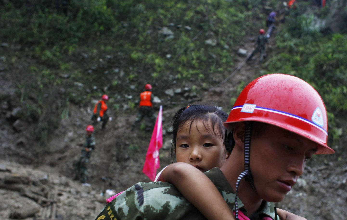 Päästetöötaja kannab riigi edelaosas asuva Sichuani provintsi üleujutatud mägikülast alla tüdrukut. Pilt on illustreeriv.