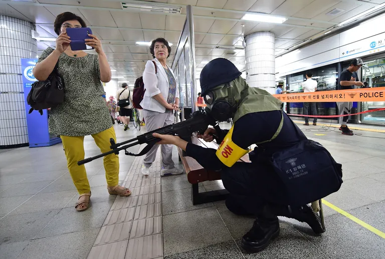 Õppuste ajal metroopeatusse sattunud naine, kes kasutas võimalust teha gaasimaskis politseinikust pilti.