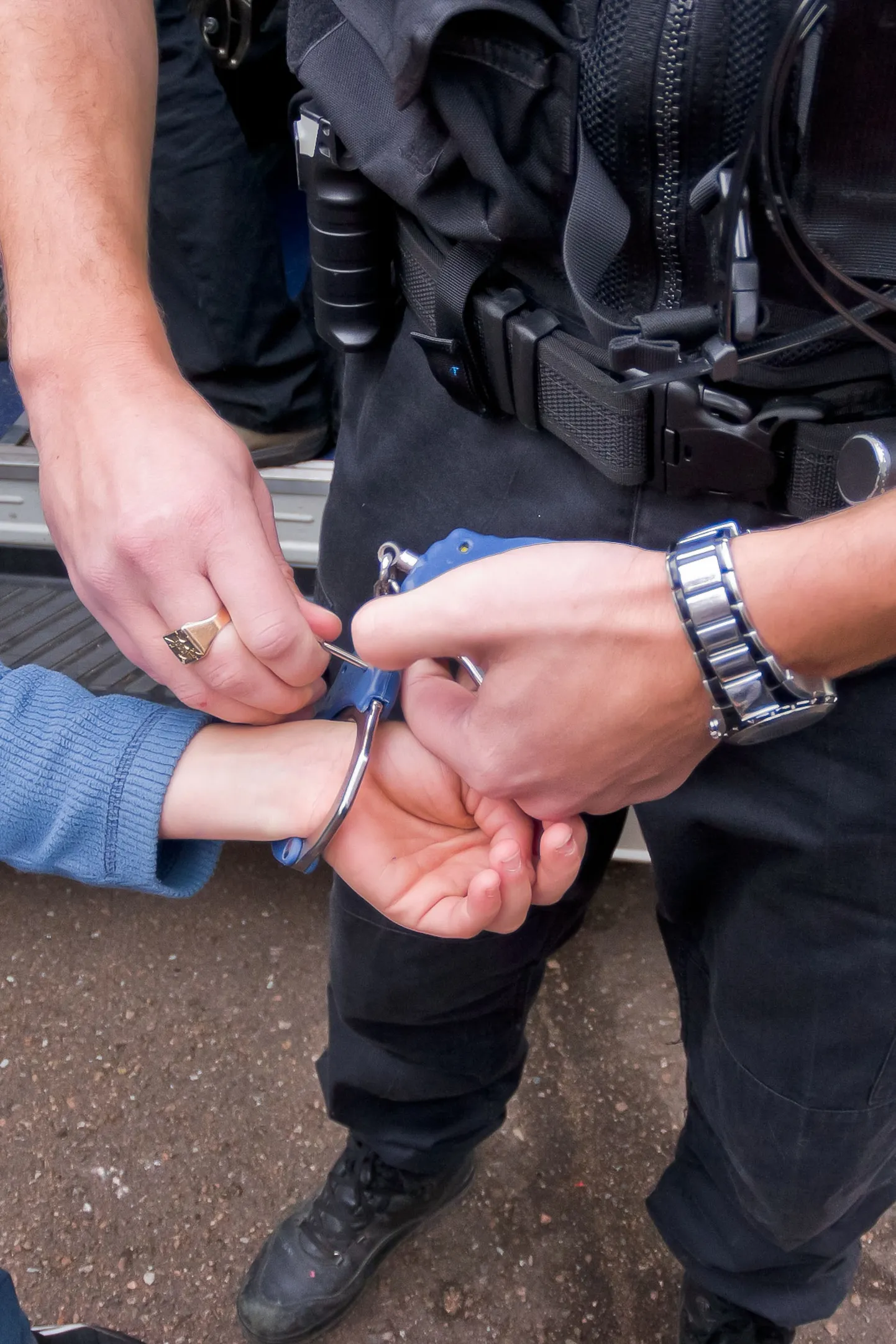 Полицейский надевает наручники на нарушителя.