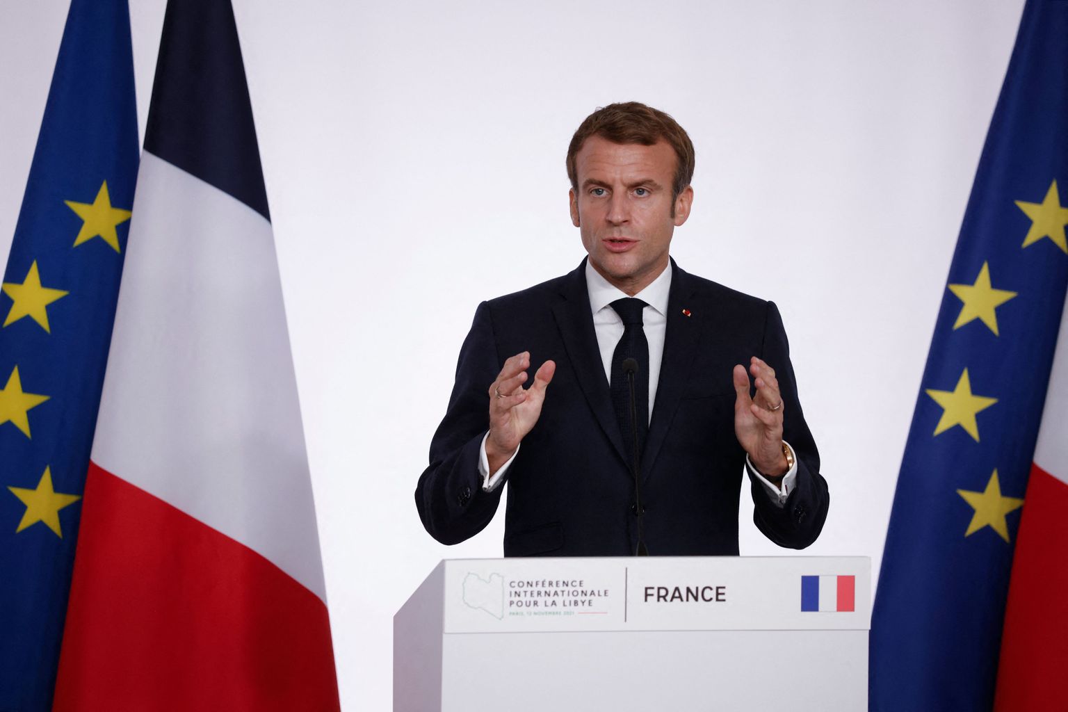 Prantsuse president Emmanuel Macron rääkimas Liibüa-teemalise konverentsi pressikonverentsil 12. novembril 2021 Pariisis. Ta kõrval on näha Prantsusmaa ja Euroopa Liidu lippe