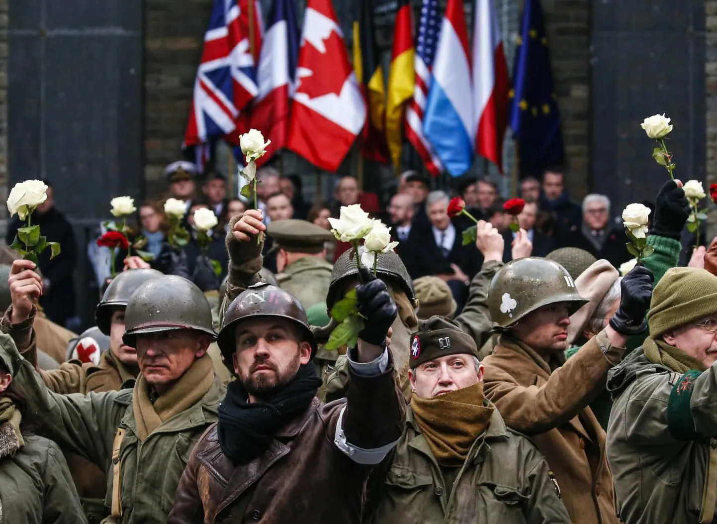 Teise maailmasõja aegseteks sõduriteks riietunud mehed asetasid mälestusmärgi juurde valged roosid.