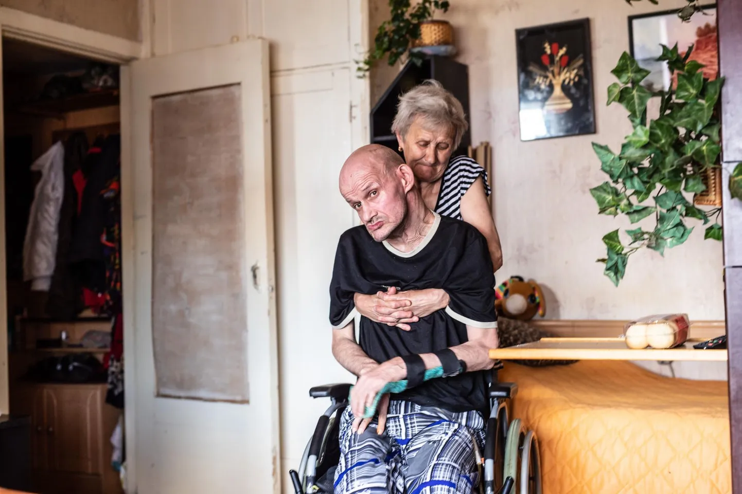 Пенсионерка Нина Головань сама перетаскивает Андрея из постели в инвалидное кресло.