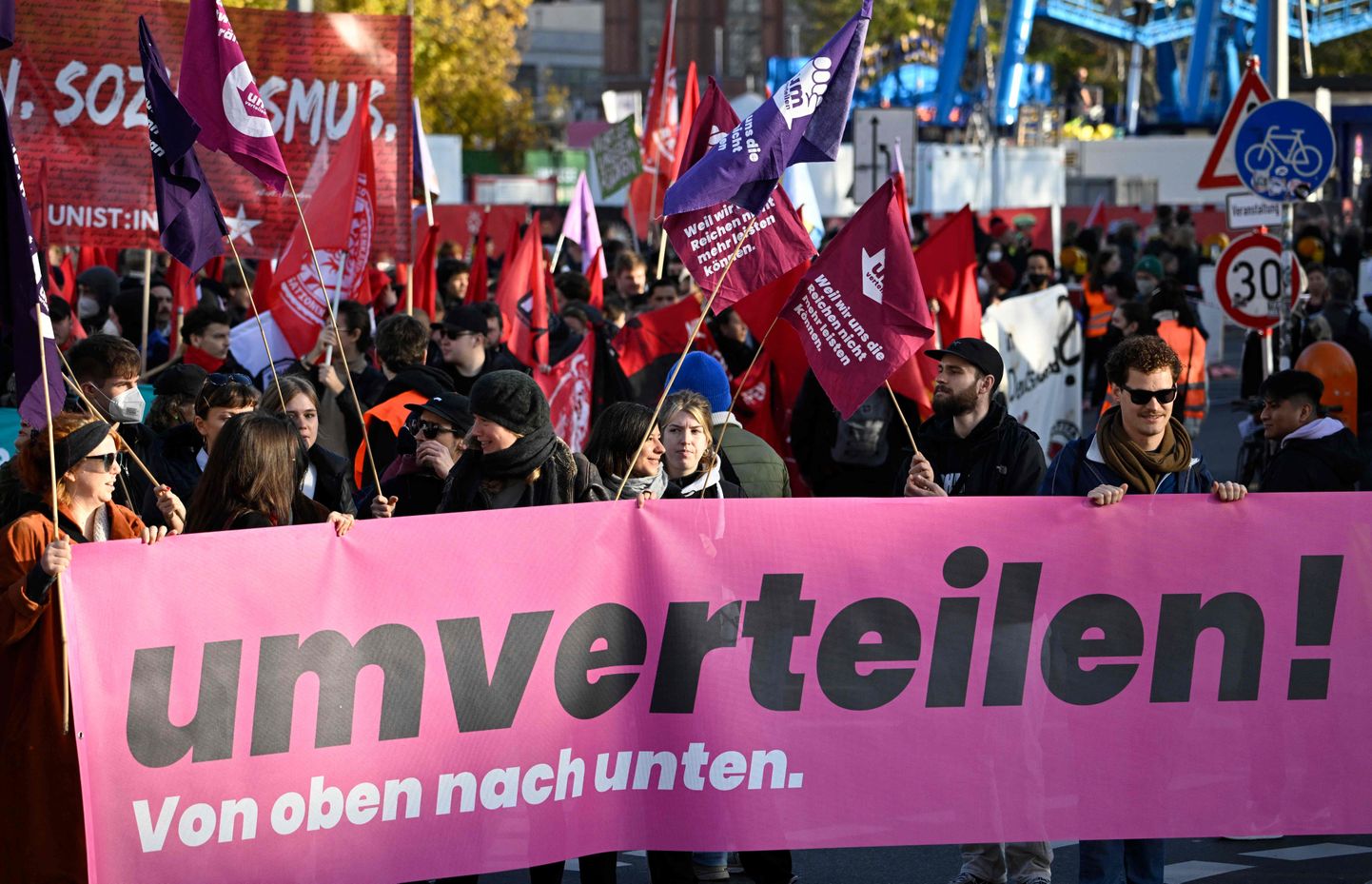 Демонстранты несут плакат с надписью «Перераспределить! Сверху вниз» во время демонстрации под названием «Umverteilen!»