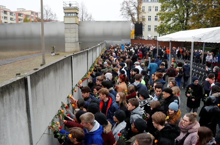 Inimesed torkamas täna roose Bernaueri tänaval oleva Berliini müüri lõigu vahedesse.