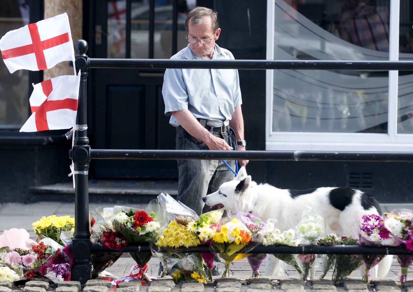 Mees uurib mõrvapaika ja ohvrite mälestuseks tänavale asetatud lilli Duke Streetil Whitehavenis.