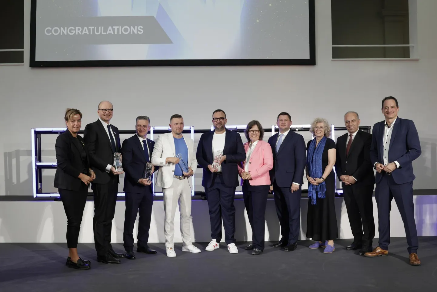 Pildil vasakult: Nordrhein-Westfaleni liidumaa majandus-, tööstus-, kliimakaitse- ja energeetikaminister Mona Neubaur; Wesseling-Knapsack LyondellBaselli tehase juht Daniel Koch; Laser ISSE Europe'i juhtivpartner Burak Celikkaya; Tactical Solutions'i tegevjuht Sverre Puustusmaa (valges);​ Herbeder Holzwarenkontori tegevdirektor Jörn Brenscheidt; ​Dortmundi käsitöökoja asepresident Kerstin Feix; Eesti suursaadik Saksamaal Kalvi Nõmmägi; Madalmaade Kuningriigi peakonsul Düsseldorfis Hannah Tijmes; ​ATIAD juhatuse esimees Aziz Sariyar; NRW tegevjuht Felix Neugart