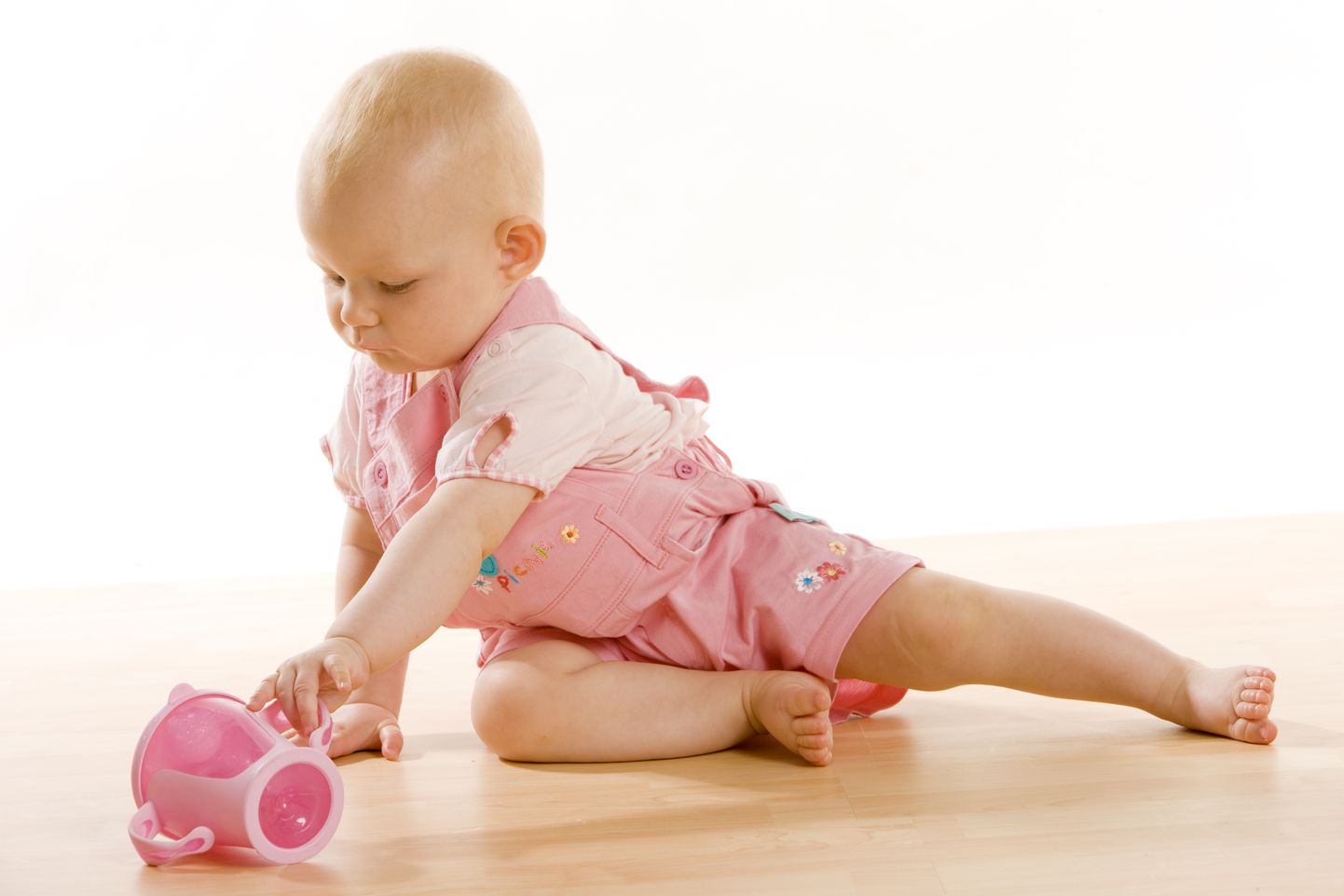 baby girl with a mug sitting on the floor