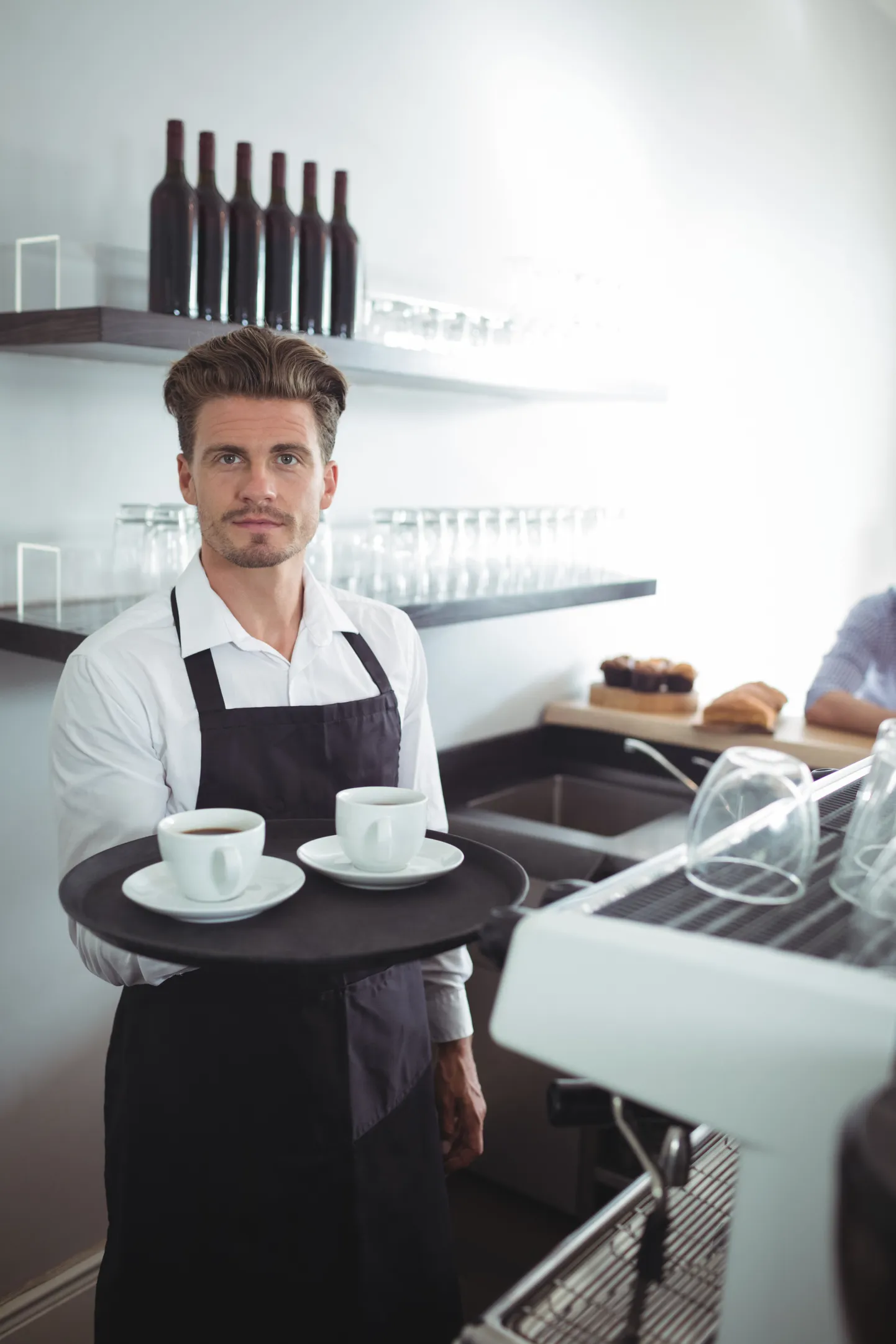 Waiter holding coffee in tray at counter
