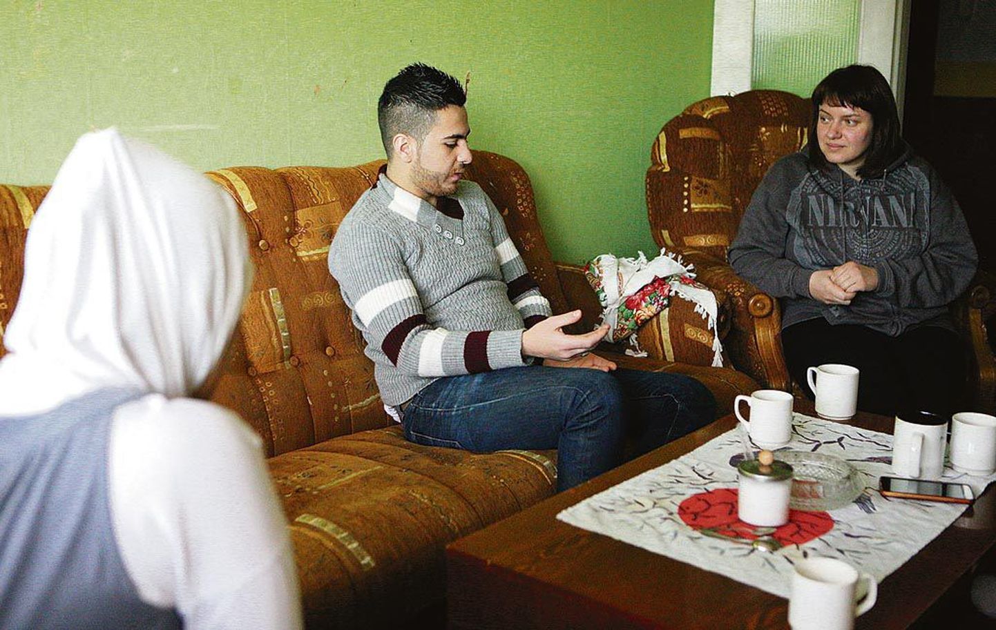 (Paremalt) Tõlkida aitav Alla ja Omar süürlaste Pärnu kodu elutoas. Omari abikaasa Hiba (vasakul) on tagasihoidliku loomuga ja ei soovinud oma näoga pildile jääda.