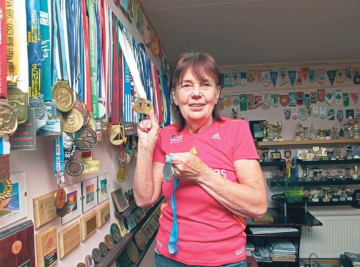 Leili Teeväli hoiab käes medalit, mille sai pärast 50. maratoni läbimist, ja näitab samal ajal mitme riigi medaleid.