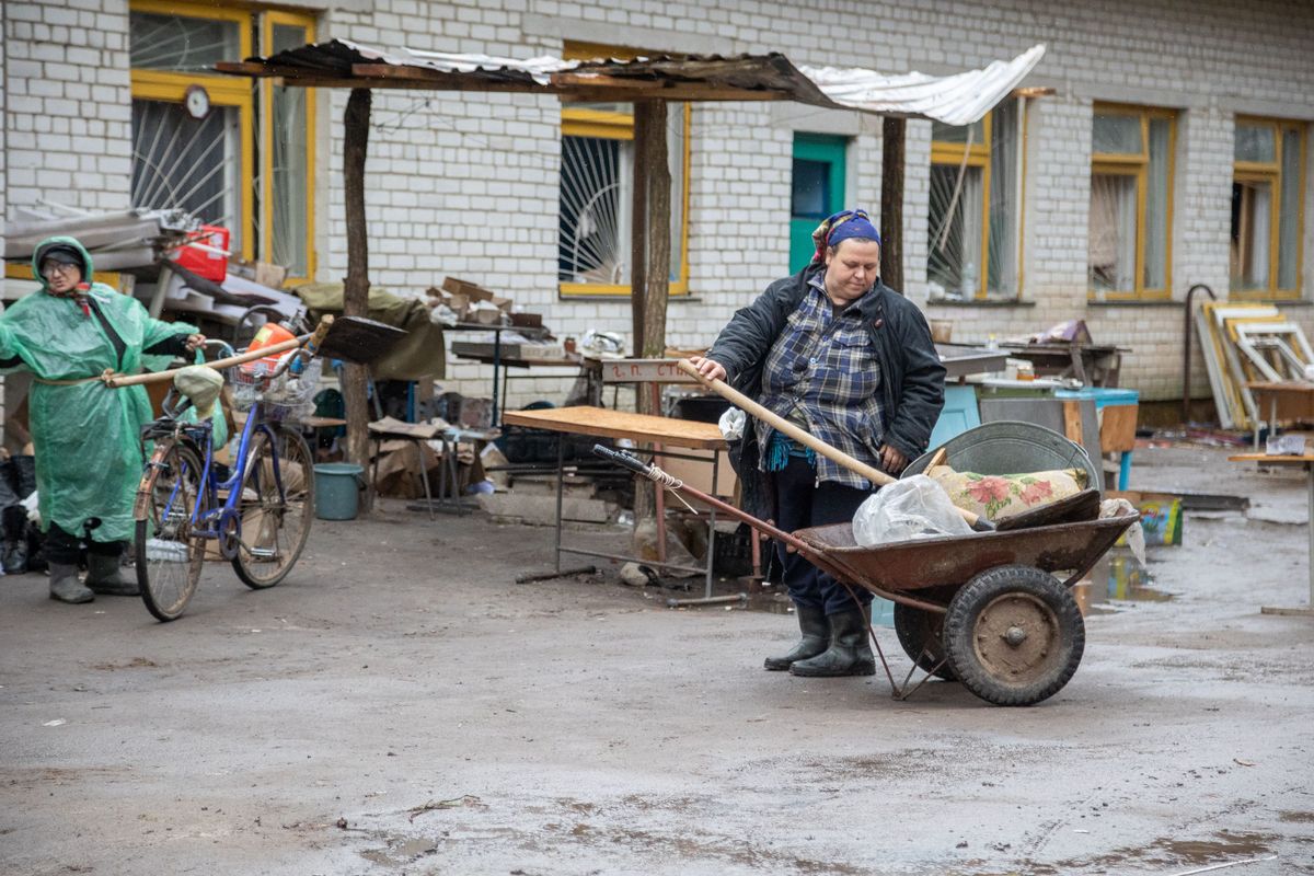 Вот так выглядит двор, куда выпускали узников подвала. В настоящее время жители поселка Ягодное, в том числе Ирина (справа), пытаются убрать брошенный российскими солдатами мусор. 