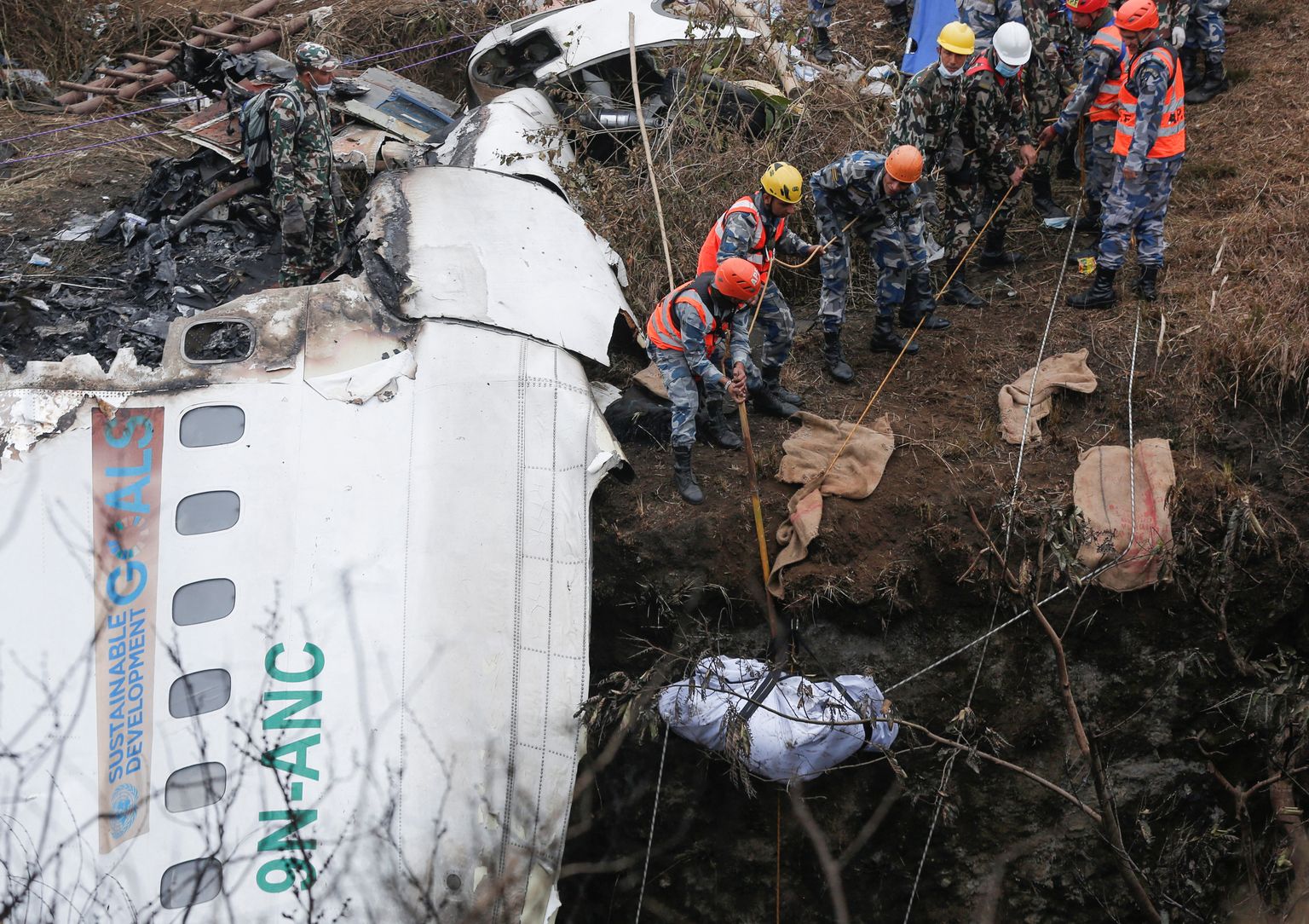 Päästetöötajad toimetavad Nepali lennuõnnetuse paigalt ära pardal viibinud inimese surnukeha.