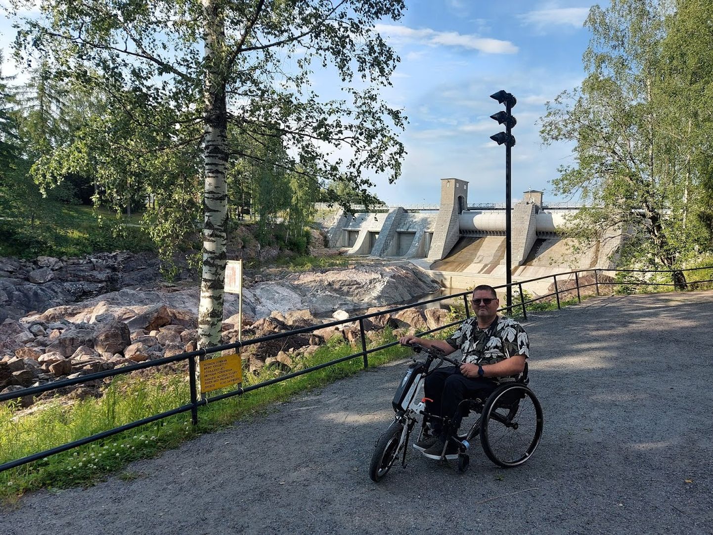 Liikumispuudega inimeste eestkõneleja Arko Vool on kogenud matkaja. Looduse imetlemine on alati reisi oluline osa. Ilmateade on ratastooli kasutavale matkajale oluline info; kõige parem on kuiv ja soe ilm. Pildil Arko Imatra kose juures Soomes, Lõuna-Karjalas.
