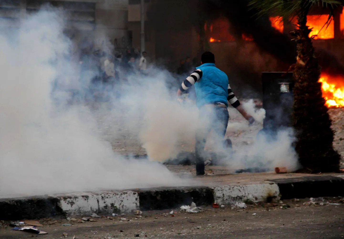 An Egyptian protester throws back a tear gas canister towards police, unseen, during clashes in Port Said, Egypt, Monday, March 4, 2013. Violence between police and protesters restarted Monday in the restive Suez Canal city of Port Said, as forces lobbed tear gas and birdshots at protesters who throw firebombs at a government complex, setting parts of it on fire. (AP Photo/Ahmed Ramadan) / SCANPIX Code: 436
