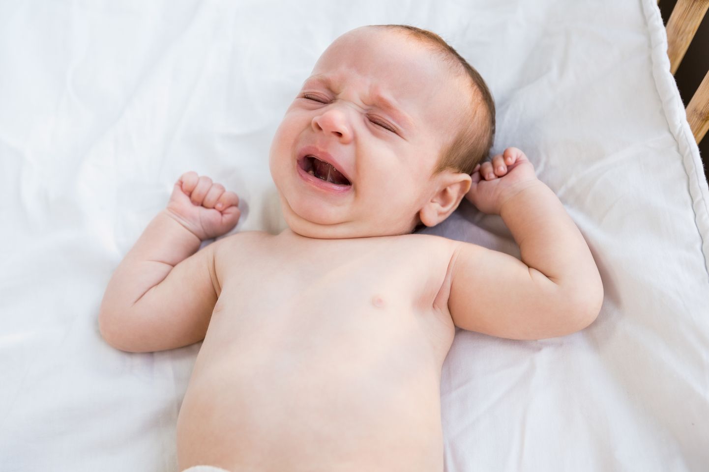 Close-up of crying baby on baby bed