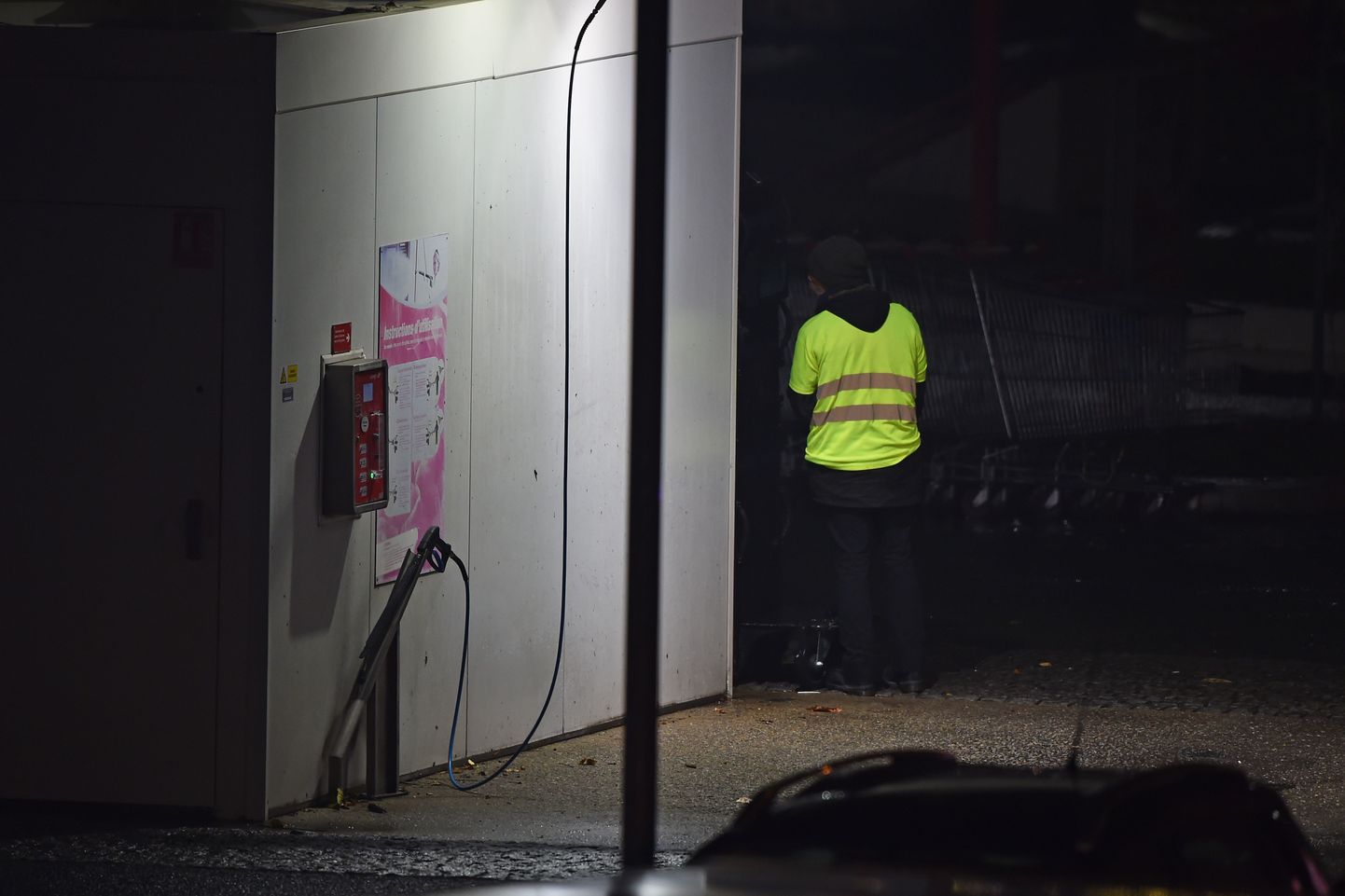A man wearing a yellow vest and reportedly wielding a grenade, which could be a tear gas, stands as police carry out an intervention at the car wash station of the Espace Anjou shopping centre in Angers, western France, on November 23, 2018. 