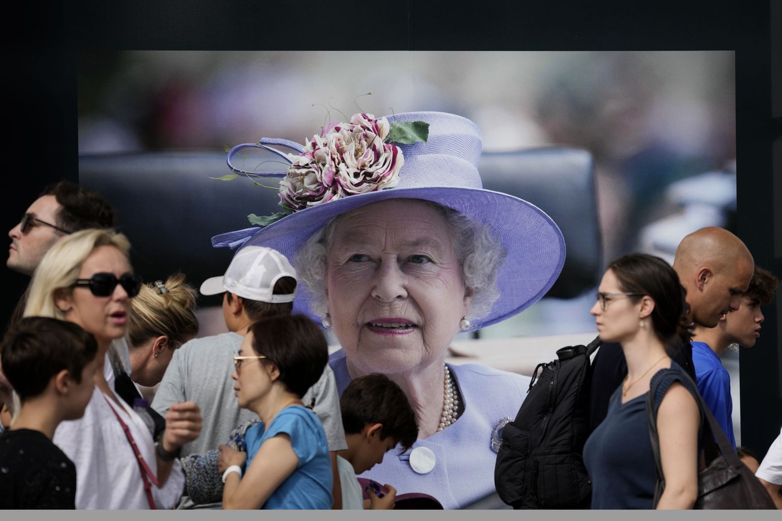 Inimesed kõndimas kuninganna Elizabeth II pildi ees. Pilt on illustreeriv.