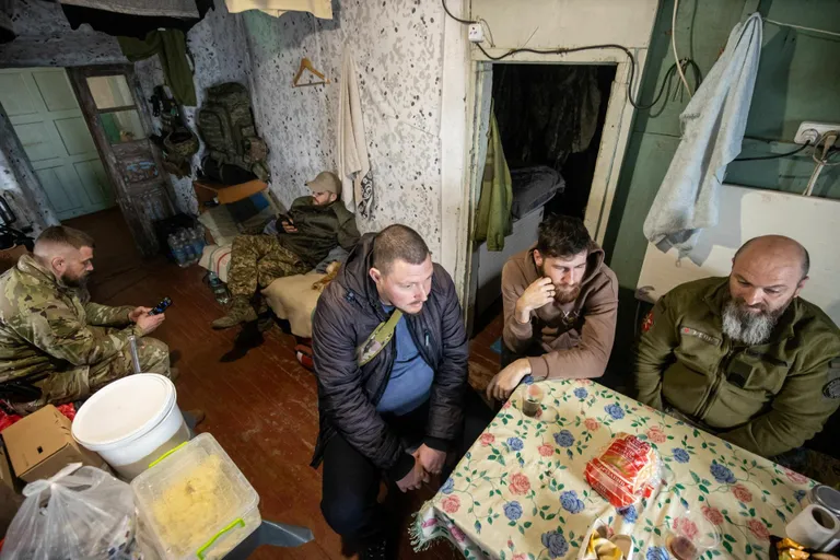 Солдаты 79-й десантной бригады Украины в пункте стабилизации ожидают раненых. За столом сидят (справа налево) фельдшер Александр и санитар Максим. Позади них, на полевой складной кровати, сидит заместитель командира медицинской роты Игорь.
