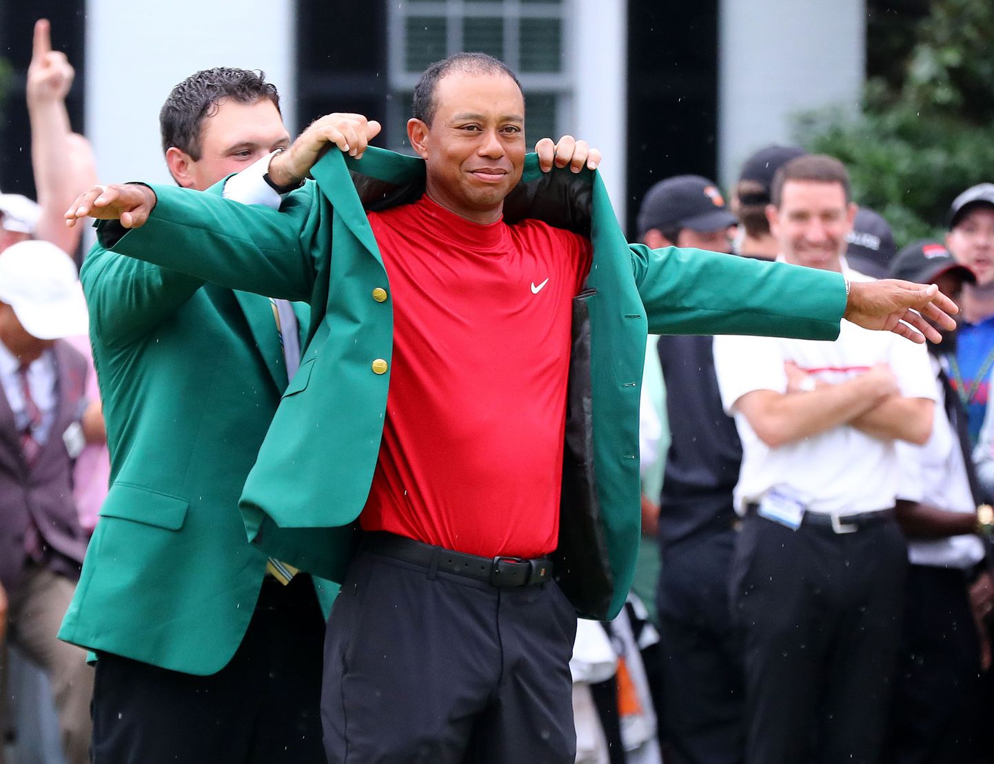 Tiger Woodsile aitab rohelist pintsakut selga Marstersi eelmise aasta võitja Patrick Reed.